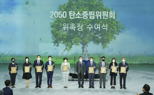 문재인 대통령이 29일 오후 서울 동대문디자인플라자에서 열린 '2050 탄소중립위원회 출범식'에 참석, 윤순진 민간위원장(왼쪽 다섯번째) 등 위원들에게 위촉장을 수여한 뒤 기념촬영을 하고 있다. 연합뉴스